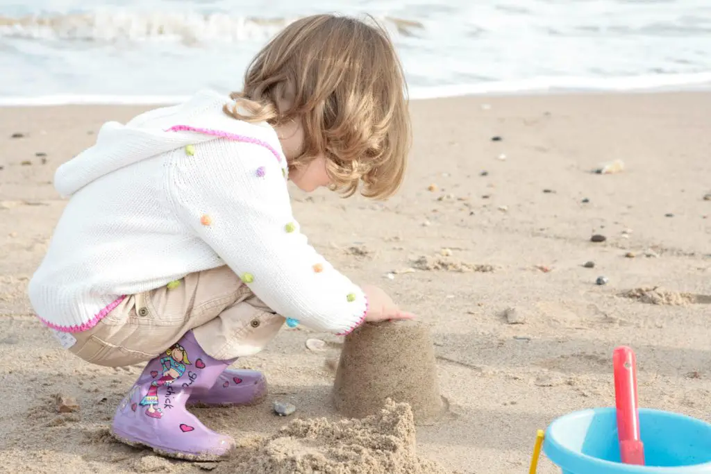 Little girl making a sandcastle at seaside
